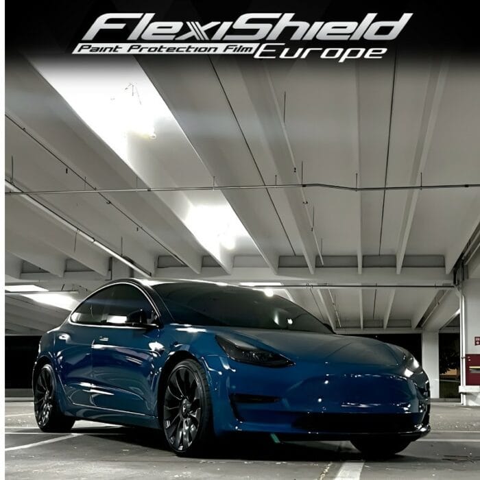 Dans un garage intérieur moderne et bien éclairé, une voiture électrique arborant une élégante finition FLEXISHIELD Cosmétique PPF CL-14 Egyptian Blue est garée. Au-dessus, une signalisation pour FlexiShield Paint Protection Film Europe garantit que son extérieur brillant et ses roues noires restent impeccables grâce à la technologie avancée Cosmétique PPF. - Tekalab