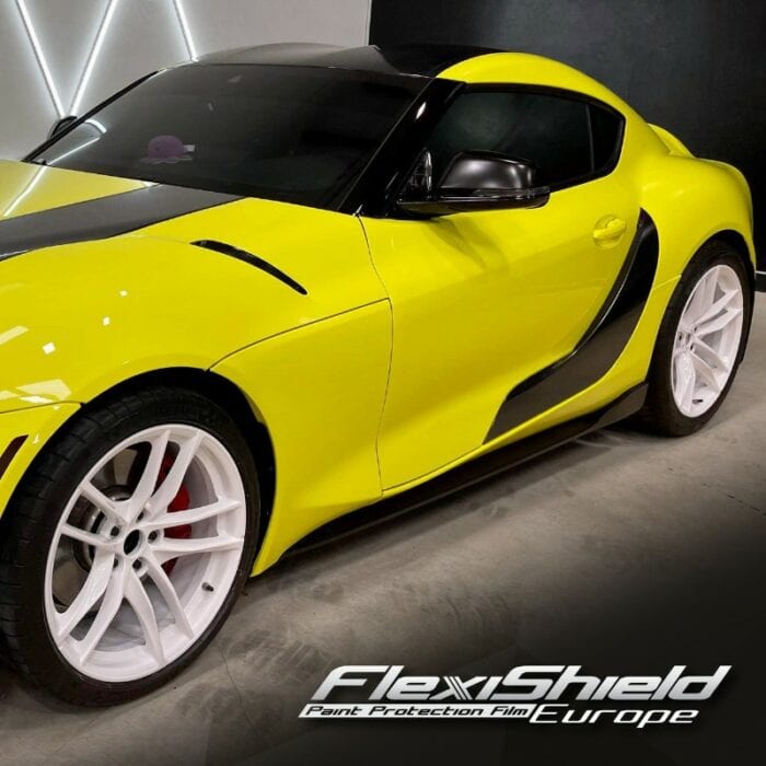 Une voiture de sport en FLEXISHIELD Cosmétique PPF CL-03 Highlighter Yellow avec des roues blanches et des accents noirs est garée à l'intérieur. Ce véhicule époustouflant présente des courbes épurées et une finition brillante, mettant en valeur son design exceptionnel. Dans le coin, le texte FLEXISHIELD Paint Protection Film Europe est visible, soulignant sa protection supérieure. - Tekalab