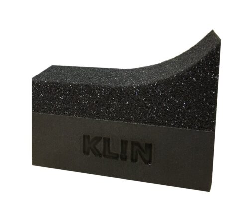 Lapplicateur Klin Sidewall Hugger pour flancs de pneus est un bloc de mousse texturé noir avec une surface inclinée présentant un dessus incurvé et une texture mouchetée. Le mot KLIN est gravé en relief sur le côté, ce qui ajoute à son motif unique. - Tekalab