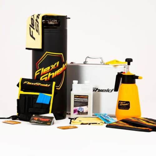 Un arrangement astucieux de produits de nettoyage automobile FlexiShield est présenté sur un fond blanc, comprenant un boîtier cylindrique, un vaporisateur à pression PPF FlexiShield de 19 L, des chiffons de nettoyage et une boîte en métal noire, jaune et blanche au design élégant. - Tekalab
