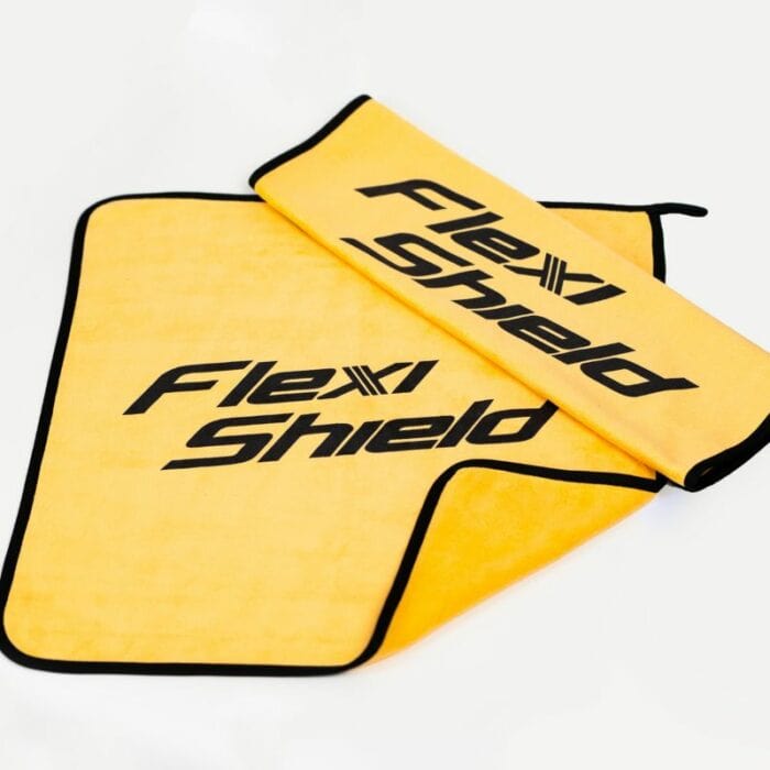 La serviette en microfibre Flexishield 40X40 est une serviette jaune et noire arborant le logo « Flexi Shield ». Elle mesure 40x40 cm et possède des bordures noires épurées qui soulignent à la fois le style et la fonctionnalité. La serviette est partiellement enroulée, reposant sur une autre partie delle-même. - Tekalab