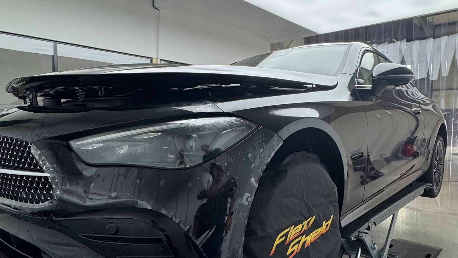 Mercedes noire en cabine, pose d'un film PPF FlexiShield sur l'aile avant